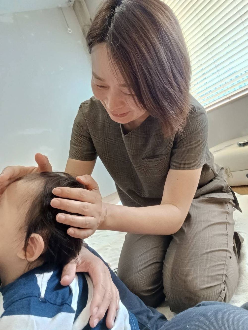 佐々木が赤ちゃんの頭にやさしく触れている様子
